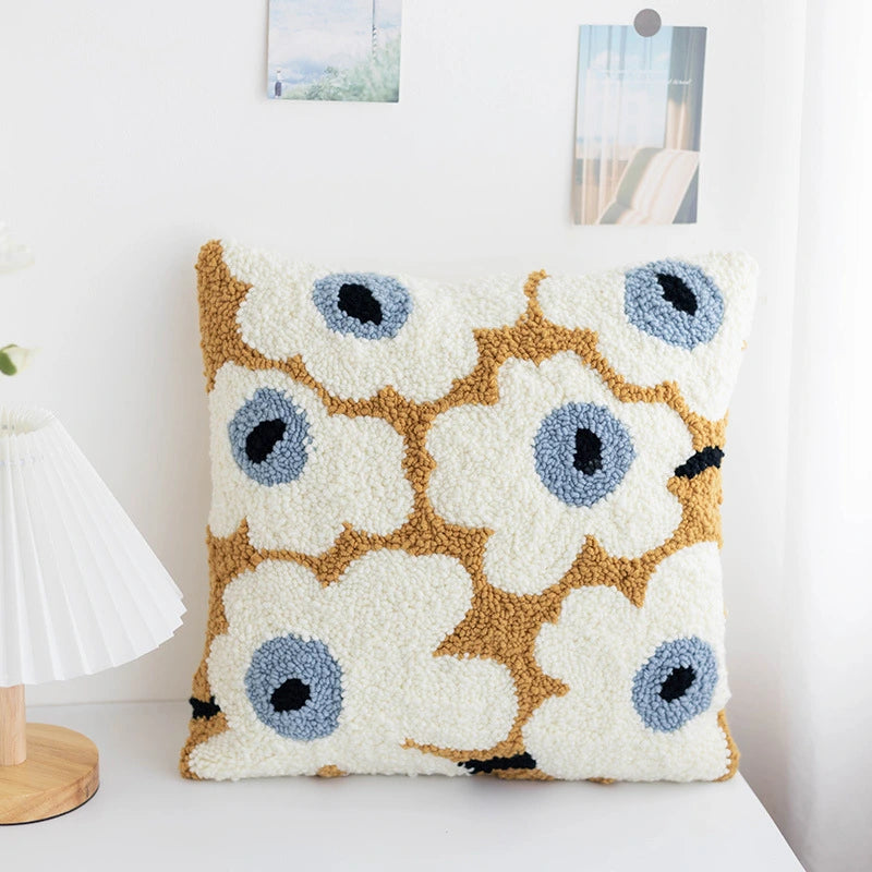 Decorative pillow with floral pattern on a white surface.A soft punch needle pillow cover featuring blooming white flowers with blue centers. Its fresh, cozy design adds a warm touch to any home décor — perfect as a cushion, pillow, or heartfelt handmade gift.