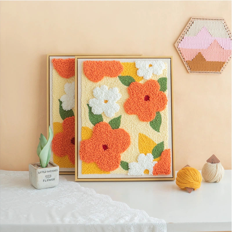 Framed floral artwork with orange, white, and yellow flowers on a beige wall.
