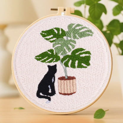 Calm Cat Punch Needles Kit — A peaceful black cat sits quietly beside a large monstera plant in a wooden pot. The lush green leaves and soft background create a calm and cozy scene. Simple and elegant, this design is perfect for beginners looking to enjoy a slow, relaxing crafting experience.