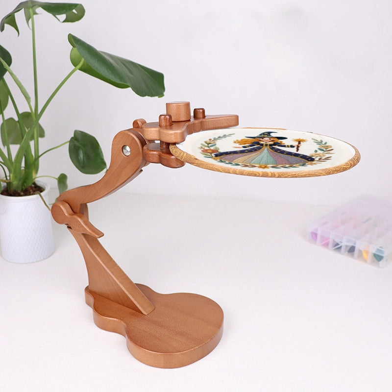 Wooden embroidery hoop stand with a plant and thread spools in the background