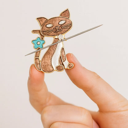 Cat-shaped brooch held by a hand against a light background