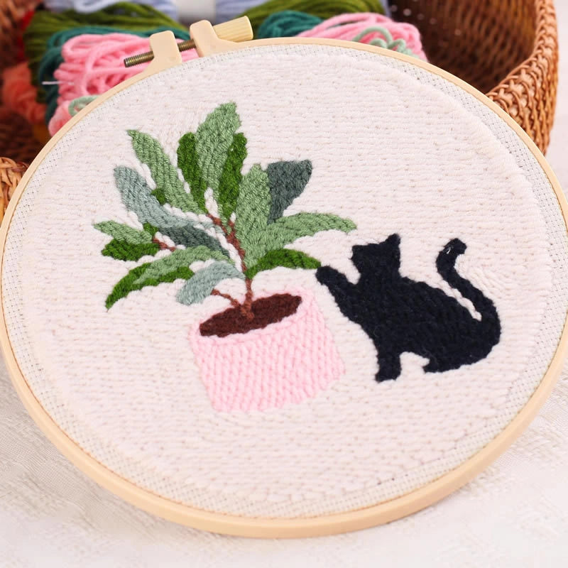 Embroidery hoop with a black cat and potted plant design.