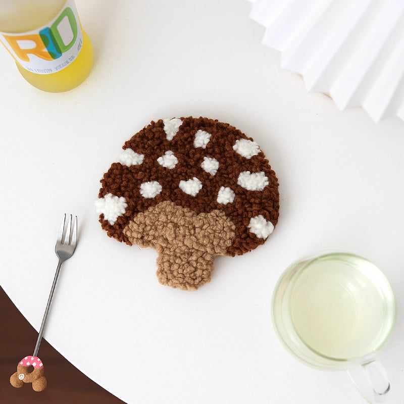 Coaster shaped like a mushroom with brown and white colors on a white surface with a fork and glass.