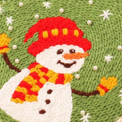 This punch needle artwork features snowman with a red hat and scarf on a green background