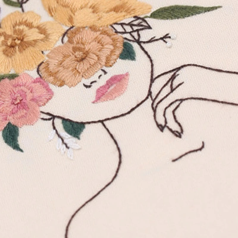 Embroidery of a face with flowers and a hand on a beige background