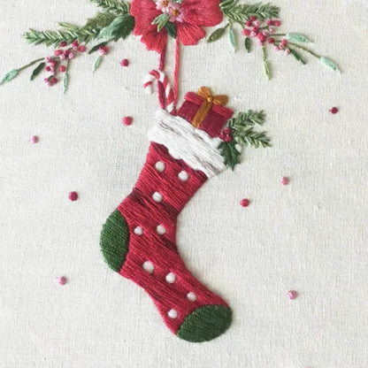 Embroidered Christmas stocking with a gift and floral decorations on a white background