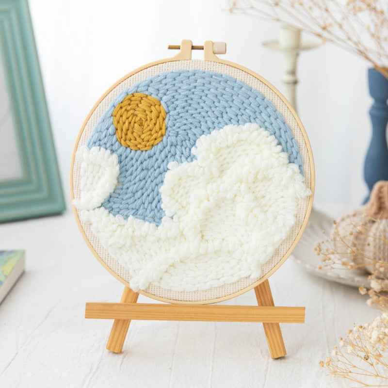 Handmade crochet wall art with a sun and clouds on a wooden stand.