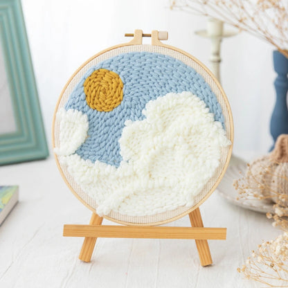 Handmade crochet wall art with a sun and clouds on a wooden stand.