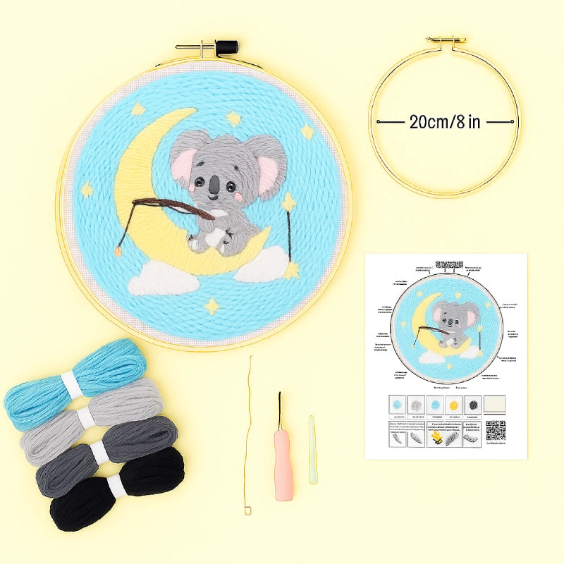 Embroidery hoop with a cartoon koala design, threads, needle, and instruction sheet on a yellow background.