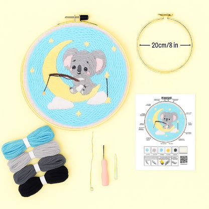 Embroidery hoop with a cartoon koala design, threads, needle, and instruction sheet on a yellow background.