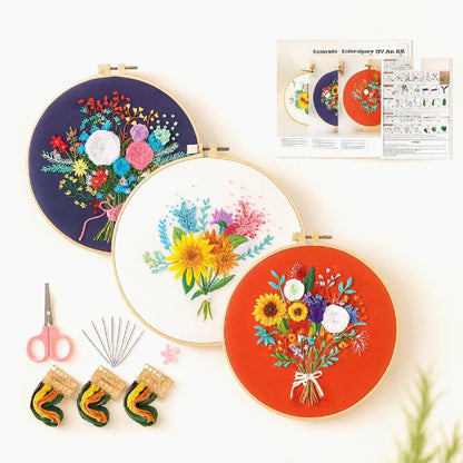Embroidery hoop set with floral designs, scissors, needles, and a pattern guide on a white background.