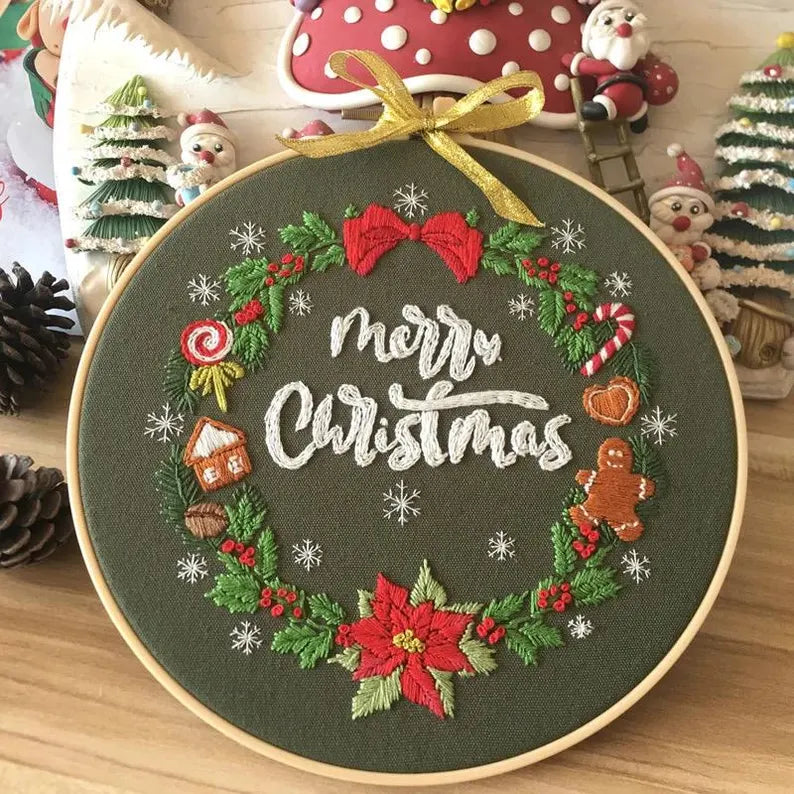 Embroidery hoop with 'Merry Christmas' design surrounded by festive decorations.