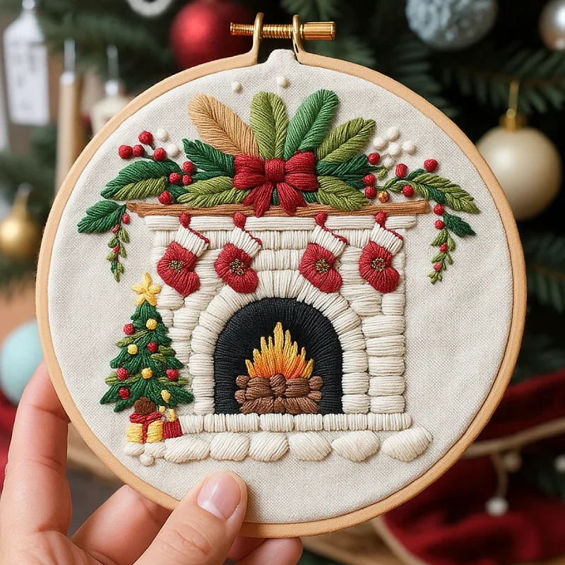 Embroidery hoop with a festive fireplace design held in front of a Christmas tree.