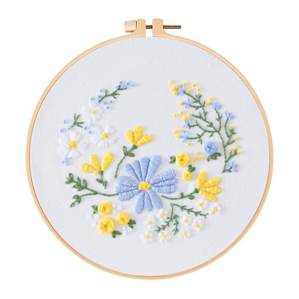 Embroidery hoop with blue and yellow floral design on a white background