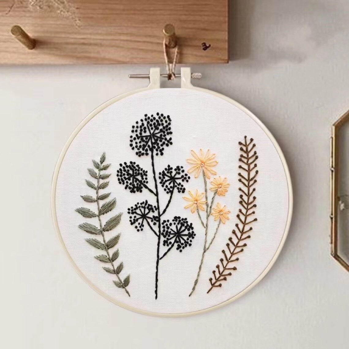 Embroidery hoop with floral and leaf patterns on a light background
