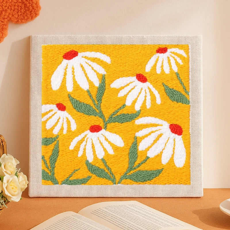 This charming punch needle artwork features white daisies with bright red centers dancing across a sunny golden-yellow background.