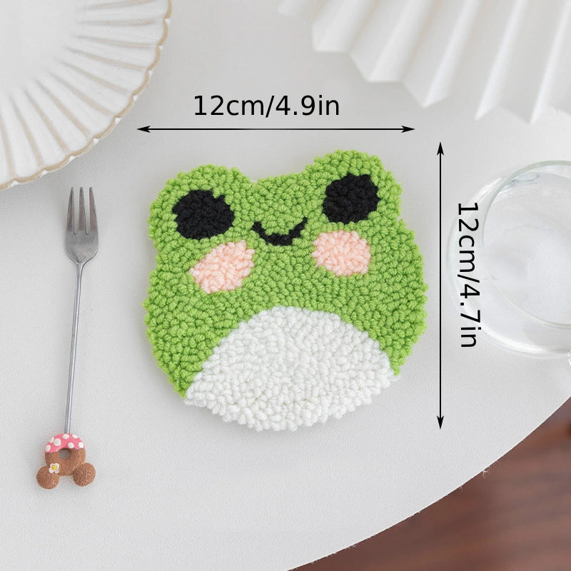 Green frog-shaped coaster with measurements on a white surface