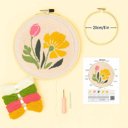 Embroidery hoop with floral design, yarn, needle, and instruction sheet on a yellow background