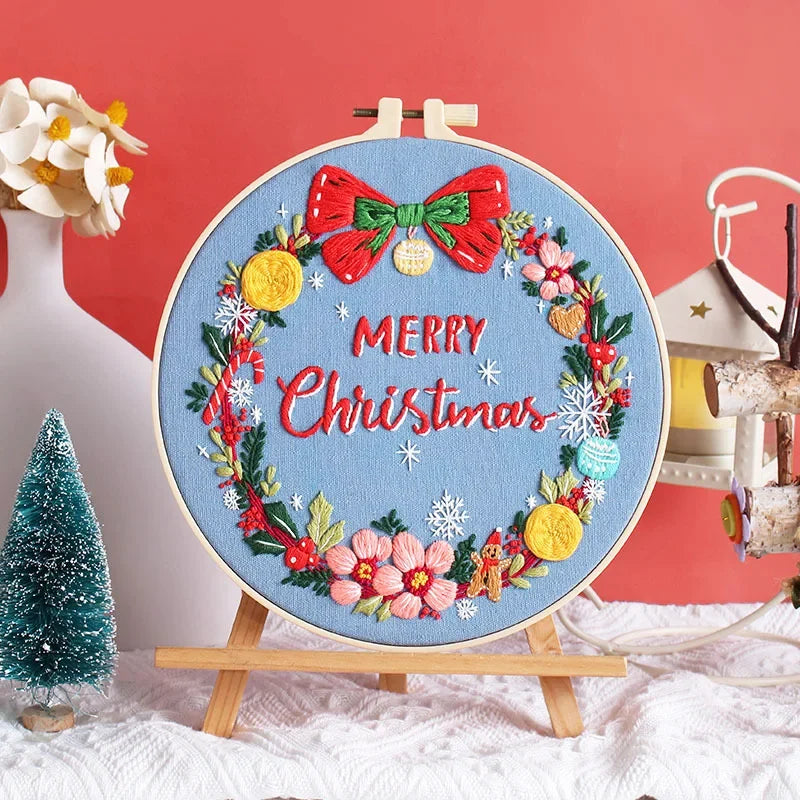 Set against a cheerful blue background, this design features a festive red bow and “Merry Christmas” message surrounded by golden ornaments, pink blossoms, gingerbread men, and delicate snowflakes. It captures the warmth and joy of the holiday season — perfect for Christmas home décor or as a heartfelt handmade gift for someone special.