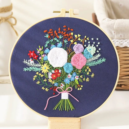 The Midnight Garden Bouquet features a stunning arrangement of hand-embroidered flowers on a deep navy background — elegant and serene like a quiet night sky.
At its heart bloom white roses of purity and hope, surrounded by pink and lavender blossoms that add a touch of romance.
Tiny red and blue flowers bring playful brightness, while a delicate pink bow ties the bouquet together, adding a soft, graceful charm.
It’s a perfect balance of colour, texture, and emotion — like capturing the calm beauty of a mid