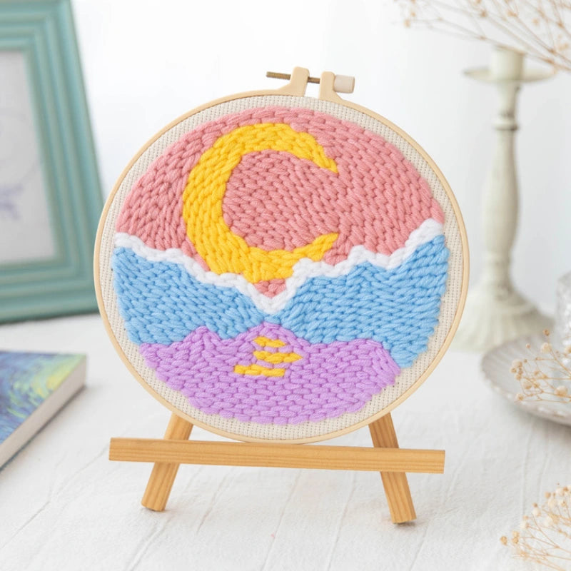 Colorful woven art piece with a crescent moon design on a wooden stand.