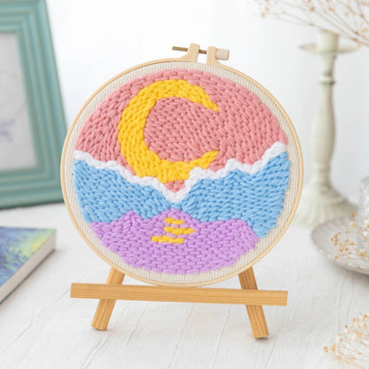 Colorful woven art piece with a crescent moon design on a wooden stand.
