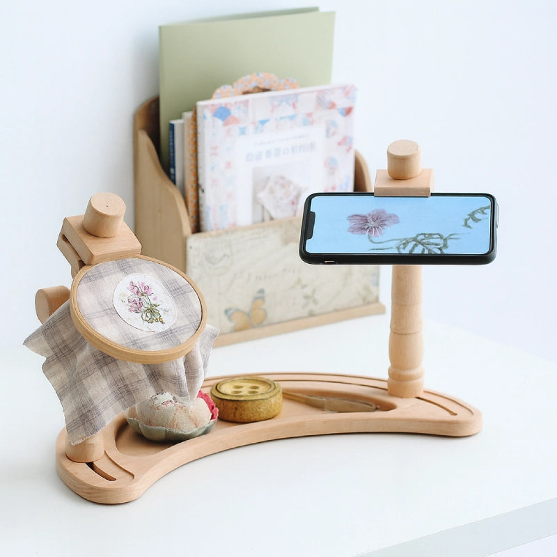 Colorful butterfly brooch on a light gray fabric background with embroidery hoop and threads.