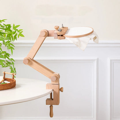 Wooden clamp lamp with white shade on a white surface with a plant in the background