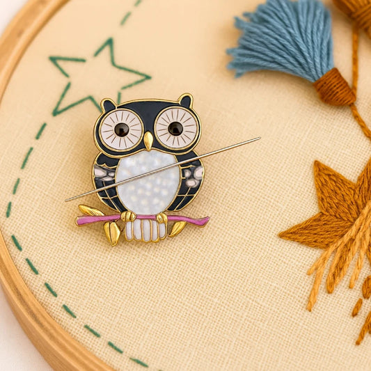 Owl-shaped brooch on a embroidery hoop with yarn and thread.
