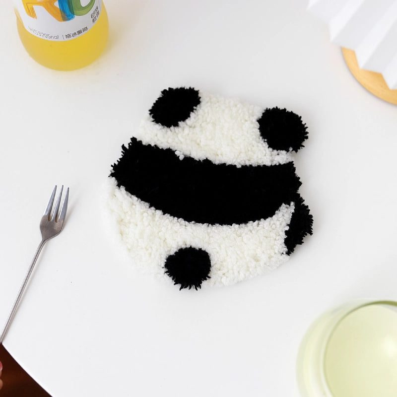 Panda-shaped rice dish on a white plate with a fork and other items in the background.
