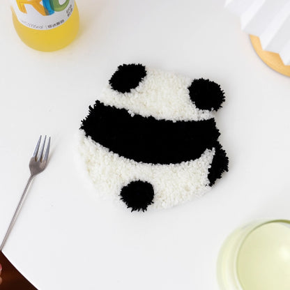 Panda-shaped rice dish on a white plate with a fork and other items in the background.
