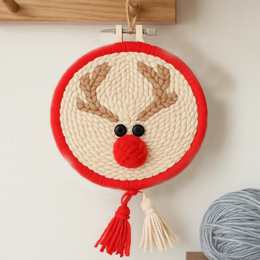Woven reindeer decoration with red border and tassel on a white wall.
