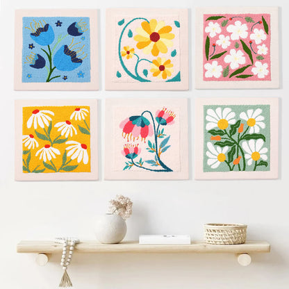 Set of six colorful floral artworks on a wall above a shelf with decorative items.