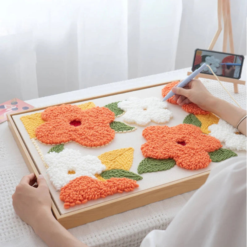 Person working on a floral crochet project with a smartphone for reference.