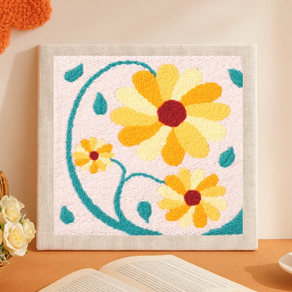 This lovely punch needle artwork features three bright golden-yellow flowers with deep red centers and curved teal stems and leaves dancing gracefully on a soft beige background. The warm, cheerful tones bring a sunny and uplifting vibe, making it a perfect piece to brighten up any cozy space.