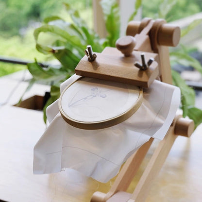 Wooden embroidery hoop with white fabric on a blurred natural background
