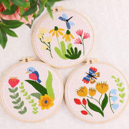 Three embroidered hoops with floral and butterfly designs on a light background.