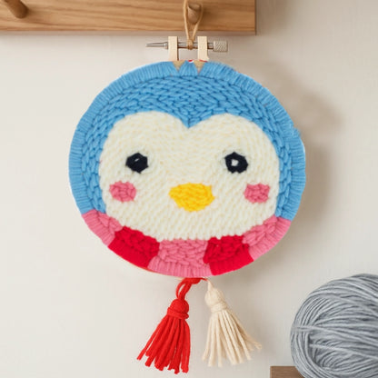 Crocheted penguin ornament with a tassel on a wooden surface