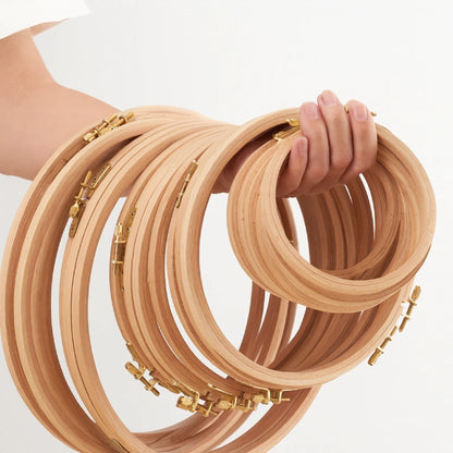 Wooden embroidery hoops held by a hand on a white background